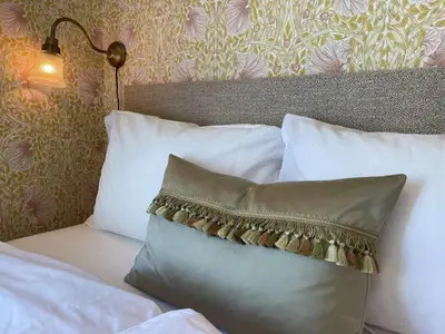a bed with white pillows and a headboard with a lamp at Jugend 1903 in Ålesund