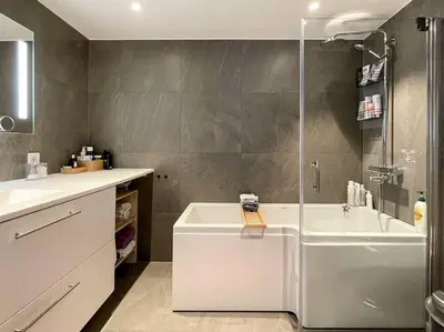 a bathroom with a shower and a tub and a sink at Modern 4 bedroom townhouse with garden and indoor car park in Trondheim