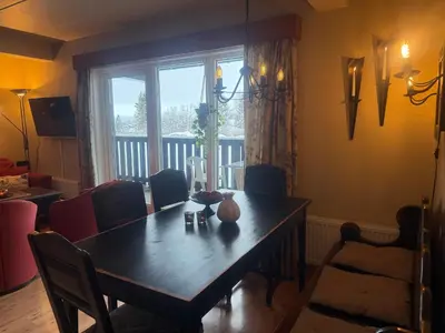 a dining room table with chairs and a large window at Charming Ground-Floor Apartment In Beitostølen With Terrace in Beitostøl