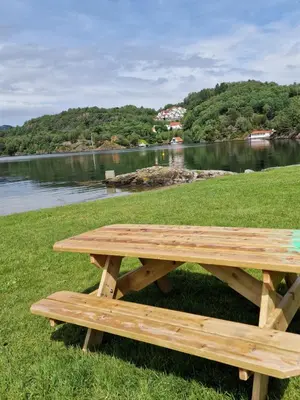 a wooden picnic table sitting next to a lake at Eidsvåg in Bergen