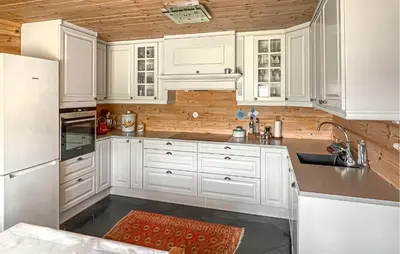 a white kitchen with white appliances and wooden walls at 3 Bedroom Stunning Home In Vossestrand in Vossestrand
