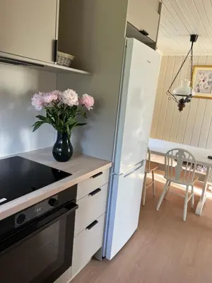 a kitchen with a white refrigerator and a vase with pink flowers at Haukedalen mountain panorama river view in Holsen