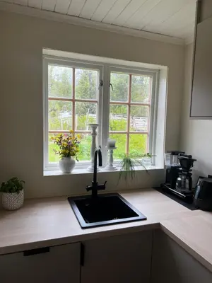 a kitchen counter with a sink and two windows at Haukedalen mountain panorama river view in Holsen