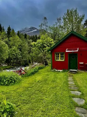 a red barn with a green door in the grass at Haukedalen mountain panorama river view in Holsen