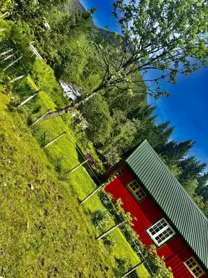 a red building with a green roof in the grass at Haukedalen mountain panorama river view in Holsen