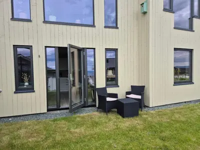a building with two chairs and a table outside at New and fresh apartment, free parking and ocean view in Trondheim