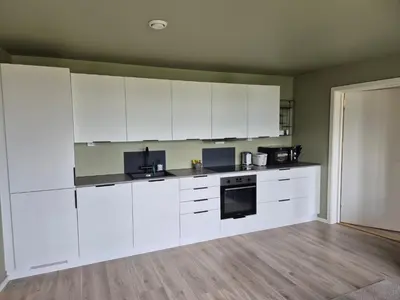 an empty kitchen with white cabinets and appliances at New and fresh apartment, free parking and ocean view in Trondheim