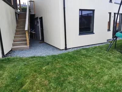 a side view of a house with a grass yard at New and fresh apartment, free parking and ocean view in Trondheim