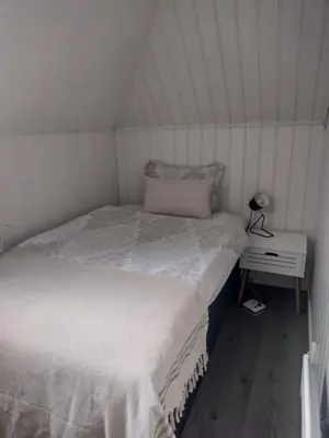 a small bedroom with a bed and a night stand at Light terrace city apartment Alesund in Ålesund