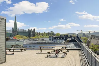 a balcony with picnic tables and a view of a city at Penthouse in Trondheim City Centre in Trondheim