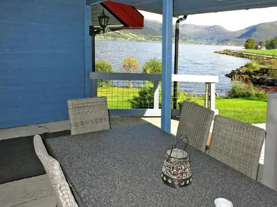 a table and chairs on a porch with a view of the water at Holiday Home Strand by Interhome in Vassenden