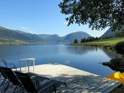 a table and chairs sitting on a dock next to a lake at Holiday Home Strand by Interhome in Vassenden