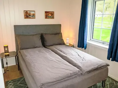 a bed in a bedroom with blue curtains at Holiday Home Greenhouse by Interhome in Onarheim