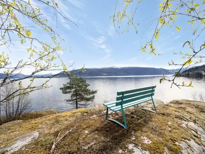 a green bench sitting on the side of a lake at Holiday Home Sandviki by Interhome in Balestrand
