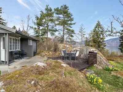 a house with a deck with a table and chairs at Holiday Home Sandviki by Interhome in Balestrand