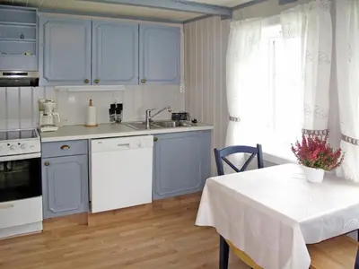 a kitchen with blue cabinets and a table with a white table cloth at Holiday Home Laksevågen by Interhome in Bruntveit