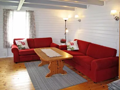 a living room with a red couch and a coffee table at Holiday Home Laksevågen by Interhome in Bruntveit