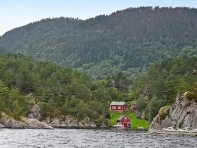 a red house on the shore of a body of water at Holiday Home Laksevågen by Interhome in Bruntveit