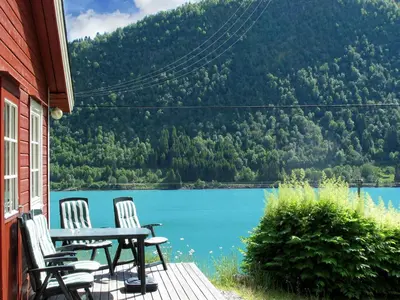 a table and chairs on a porch with a view of a lake at Holiday Home Pærehagen by Interhome in Balestrand