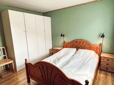 a bedroom with a wooden bed and a green wall at Holiday Home Pærehagen by Interhome in Balestrand