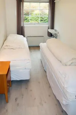 two beds in a room with a table and a window at Holiday Home Blåsenberg by Interhome in Bø