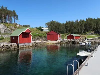 a marina with red buildings and a boat in the water at Holiday Home Nesjevik by Interhome in Bø