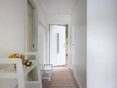 a hallway with white walls and a white table and chair at Holiday Home Lange by Interhome in Bømlo