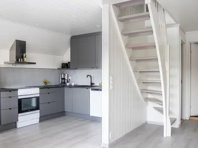 a kitchen with white cabinets and a spiral staircase at Holiday Home Lange by Interhome in Bømlo