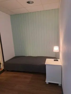 a bedroom with a bed and a table with a lamp at Haukeli hotell leilighet in Haukeligrend
