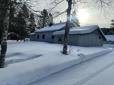 a barn covered in snow next to some trees at Hytte Elvdal in Nymoen