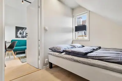 a small bedroom with a bed and a chair at Luxury Suite in Charming Area in Bergen