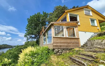 a yellow house on the side of a hill at 1 Bedroom Stunning Home In Haugesund in Haugesund
