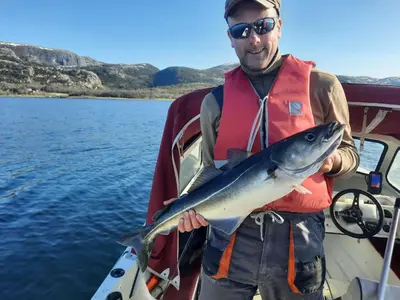 a man holding a fish on a boat at Matthias Hytte in Fevåg