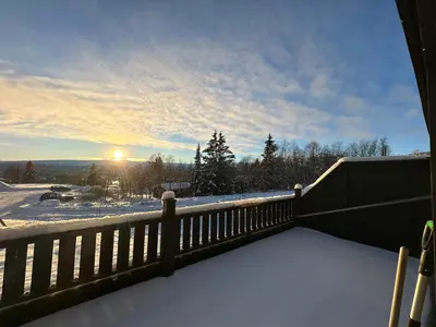 a snow covered balcony with the sun in the sky at Family-Friendly Apartment Close To Nature in Beitostøl