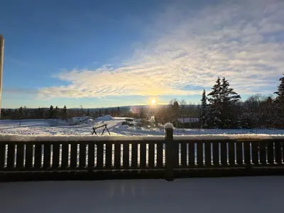 a view of a snow covered field with the sun setting at Family-Friendly Apartment Close To Nature in Beitostøl