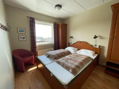 a bedroom with a bed with a red chair and a window at Central Apartment With 3 Bedrooms And Balcony in Beitostøl
