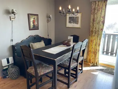 a dining room with a table with chairs and a window at Central Apartment With 3 Bedrooms And Balcony in Beitostøl