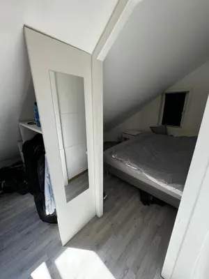 a bedroom with a mirror next to a bed at Spacious and central apartment I 250m from Bryggen in Bergen