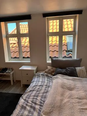a bedroom with two windows and a bed and a table at Spacious and central apartment I 250m from Bryggen in Bergen