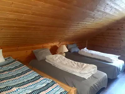 two beds in a room with wooden walls at Oynø in Etnesjøen