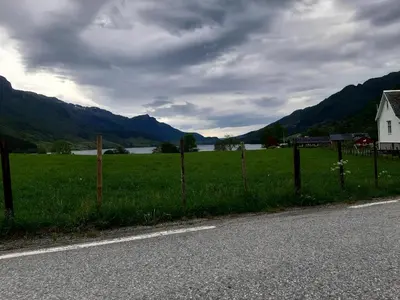 a fence on the side of a road next to a field at Oynø in Etnesjøen