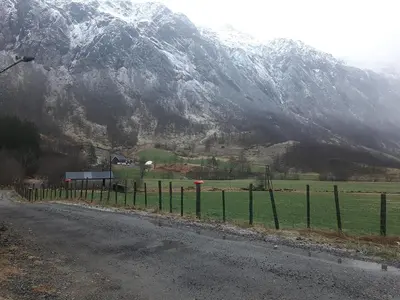 a fence on the side of a road with a mountain at Oynø in Etnesjøen