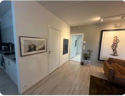 a living room with a couch and paintings on the wall at Moderne Leilighet in Stord