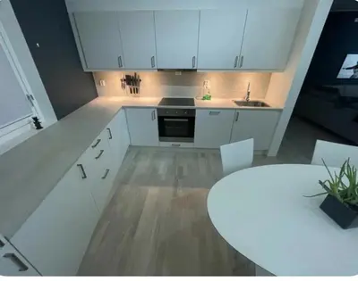 a kitchen with white cabinets and a white table at Moderne Leilighet in Stord