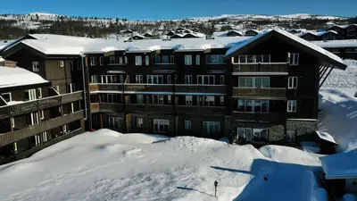 a large building in the snow with snow covered roofs at Family-Friendly Apartment Steps From Everything in Beitostøl