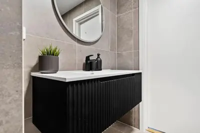 a bathroom with a black and white sink and a mirror at Premium Bergen Suite in Bergen