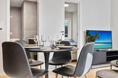 a dining room with a table and chairs and a television at Premium Bergen Suite in Bergen