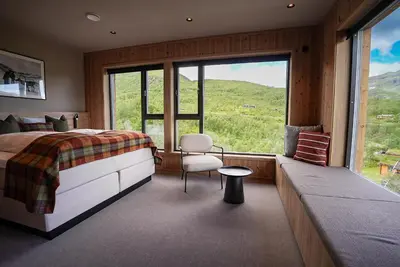 a bedroom with a bed and a chair and a large window at Filefjellstuene Hotel in Tyinkrysset