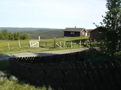 a fence in front of a barn and a house at Hytte på fjellet, med mange turmuligheter ! in Gol