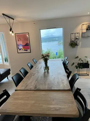 a large wooden table with chairs and a vase of flowers at Villa med fantastisk uteplass! 10 sengeplasser! in Ålesund